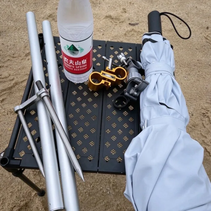 Beach umbrella with screw sand anchor, spare pole sections and tilt clamp laid out before use