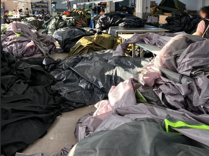 Cut canopy and tent panels staged on the workshop floor between cutting and sewing