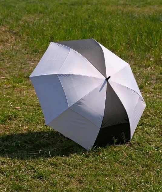 Black, white and grey panelled golf umbrella open on grass