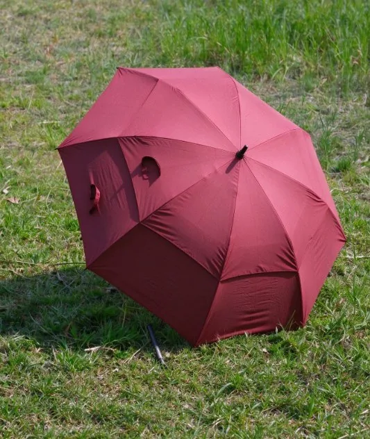 Solid-colour golf umbrella canopy opened on grass
